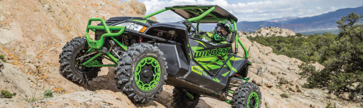 Rider in full gear in an Arctic Cat® Wildcat XLDT ATV riding off-road over rocks in the mountain